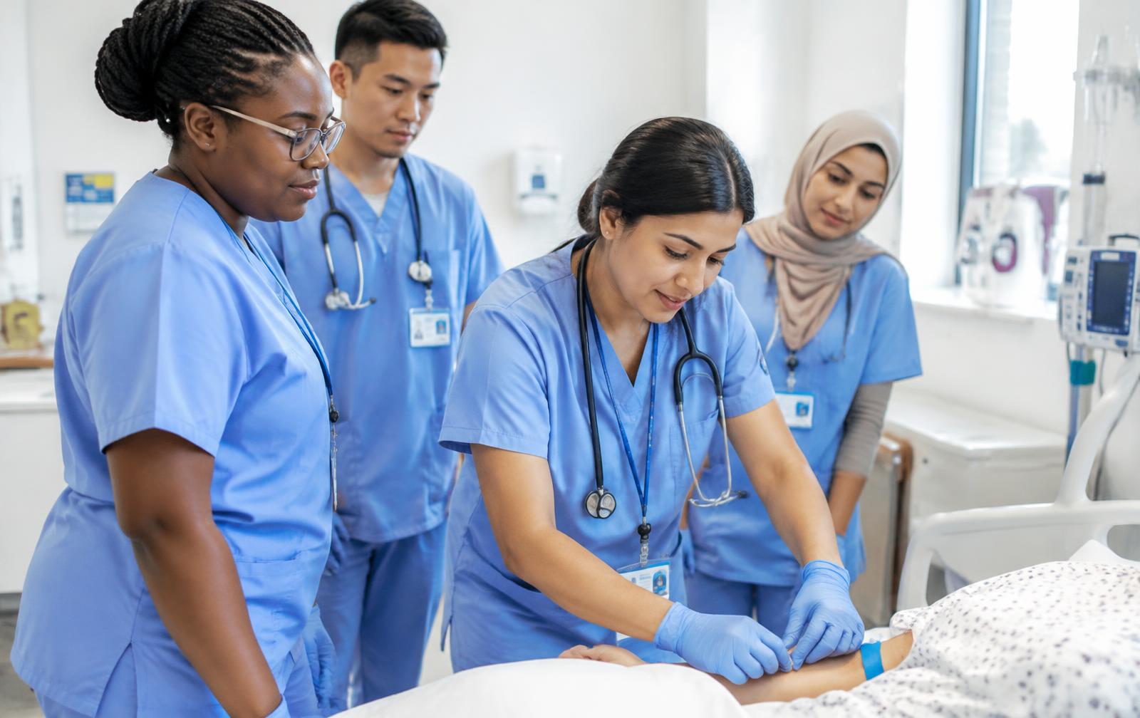 Nurses practising a clinical skill at a bedside during a ward practical